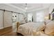 Bright bedroom featuring an accent bed frame, tray ceiling, wood floors and barn door leading to bathroom at 8778 Peachtree Park Ct, Windermere, FL 34786