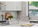 Bright kitchen offers white cabinets, marble backsplash, stainless appliances and sink with an open window view at 919 Boardman St, Orlando, FL 32804