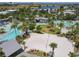 Aerial view featuring a community sand volleyball court, pools, palm trees, and resort-style amenities near a lake at 9421 Dugard Ct, Orlando, FL 32827