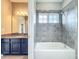 Bright bathroom with bathtub and shower featuring tiled walls, window, and granite vanity at 9421 Dugard Ct, Orlando, FL 32827