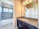 Well-lit bathroom features granite vanity, and tiled bathtub with shower, providing both style and functionality at 9421 Dugard Ct, Orlando, FL 32827
