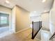 Bright hallway with neutral tones, leading to other rooms and stairs with dark wood railings at 9421 Dugard Ct, Orlando, FL 32827