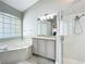 Bright bathroom featuring a soaking tub, shower with glass door and vanity with granite counter at 10356 Stone Glen Dr, Orlando, FL 32825