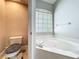 A bathtub with jets sits below a window with blinds in this bright and clean bathroom at 10356 Stone Glen Dr, Orlando, FL 32825