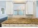 Elegant kitchen featuring granite countertops, white cabinets, and a view to the living room at 10356 Stone Glen Dr, Orlando, FL 32825