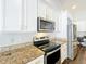 Bright kitchen featuring modern stainless steel appliances, granite countertops, and white cabinets at 10356 Stone Glen Dr, Orlando, FL 32825