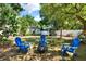 Spacious backyard featuring a privacy fence, mature trees, blue Adirondack chairs, and a fire pit at 108 S Glenwood Ave, Orlando, FL 32803