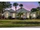 Stunning home exterior featuring a well-manicured lawn, mature trees, and a grand entrance at dusk at 11401 Willow Stowe Ln, Windermere, FL 34786