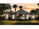 Striking home exterior enhanced by warm lighting and a picturesque sunset, highlighting the manicured lawn at 11401 Willow Stowe Ln, Windermere, FL 34786