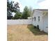 Fenced backyard features healthy green trees lining the fence and an exterior wall of the house with a window at 1160 Rolling Acres Dr, Deland, FL 32720