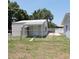 Exterior view of building with metal roof, chain-link fence, door and small concrete patio area at 1160 Rolling Acres Dr, Deland, FL 32720