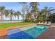 Inviting pool with blue tile accents, wood deck, lounge chairs and water views with Palm Trees at 11734 Lake Willis Dr, Orlando, FL 32821