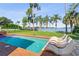 Backyard pool and deck with lounge chairs overlook a calm lake surrounded by palm trees under a clear blue sky at 11734 Lake Willis Dr, Orlando, FL 32821