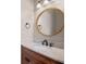 Stylish powder room featuring a wood vanity, marble countertop and a round decorative mirror at 1333 W Yale St, Orlando, FL 32804