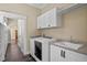 Laundry room with front load washer and dryer, sink and white cabinetry and access to hallway at 1333 W Yale St, Orlando, FL 32804