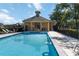 Community pool with blue water, tanning chairs, and pool house on a sunny day at 2016 Cypress Bay Blvd, Kissimmee, FL 34743