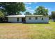 Rear view of the home displaying the spacious backyard with healthy grass, neutral paint and patio at 219 Stribling Dr, Auburndale, FL 33823