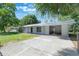 Well-maintained single-story home with a metal roof, carport, and lush green lawn surrounded by mature trees at 219 Stribling Dr, Auburndale, FL 33823