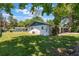 Rear exterior view features a well-maintained lawn and mature trees on this home with blue and white paint at 219 Stribling Dr, Auburndale, FL 33823