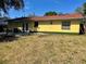 The house features a spacious backyard, concrete patio area and classic yellow siding at 235 Crabtree Ave, Orlando, FL 32835