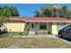 Charming single-story home featuring a red roof, yellow siding, and a cozy front porch area at 235 Crabtree Ave, Orlando, FL 32835