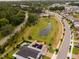 Aerial view of a community with lush greenery, a pond, and well-maintained homes with solar panels and pools at 2683 Bobcat Chase Blvd, Oakland, FL 34787