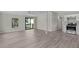 Bright, open living room featuring wood-look flooring, modern ceiling fan, and sliding glass doors to the outdoors at 33506 Luana Ct, Leesburg, FL 34788