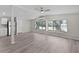 Inviting living room with large windows and light colored wood flooring, seamlessly connects to dining and kitchen at 33506 Luana Ct, Leesburg, FL 34788