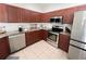 This kitchen boasts stainless steel appliances, warm cabinetry, granite counters, and tile flooring at 3420 Gerber Daisy Ln, Oviedo, FL 32766