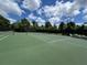 A well-maintained green outdoor tennis court surrounded by lush trees and a blue sky at 3420 Gerber Daisy Ln, Oviedo, FL 32766