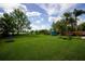Large backyard featuring lush lawn, mature trees, and play equipment at 5384 Barton Dr, Orlando, FL 32807