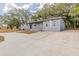 A single story home with a gray facade, large driveway, and mature trees at 5500 Riviera Dr, Orlando, FL 32808