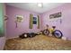 Bedroom featuring purple walls, brown carpet, and a window; two bikes and a golf bag are in the room at 5709 Breskin Dr, Orlando, FL 32839