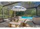 Outdoor living space showcasing a screened-in pool area with a table and chairs under a sun umbrella at 5709 Breskin Dr, Orlando, FL 32839