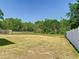 Open backyard featuring a green lawn with tall trees and partial fencing on a sunny day at 602 Milan Dr, Kissimmee, FL 34758