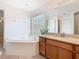 Bright bathroom features a soaking tub, granite countertop vanity, and decorative tile flooring at 602 Milan Dr, Kissimmee, FL 34758