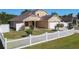 This home features an attached two-car garage, neutral paint, and an manicured front yard with a white picket fence at 602 Milan Dr, Kissimmee, FL 34758