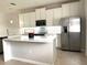 A kitchen with white cabinets, a stainless steel refrigerator, subway tile backsplash, and a quartz countertop island at 7675 Fordson Ln, Windermere, FL 34786