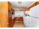 Retro kitchen featuring wood cabinets, white appliances, and an undermount sink at 770 Manor Dr, Bartow, FL 33830