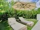 Lounge chairs sit on the grass under an umbrella, surrounded by lush greenery at 2614 Parkland Dr, Winter Park, FL 32789