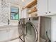 Well-lit laundry room features modern washer and dryer, stylish backsplash, and functional shelving at 2614 Parkland Dr, Winter Park, FL 32789