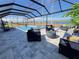 Inviting screened-in pool area with stylish patio furniture, lake view, and clear blue skies, perfect for outdoor relaxation and entertaining at 2926 Crest Wave Dr, Clermont, FL 34711