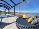 Relaxing poolside lounge area with a daybed, set against a backdrop of serene lake views, all within a screened-in enclosure at 2926 Crest Wave Dr, Clermont, FL 34711