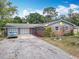 Charming brick house with a two-car garage and mature landscaping on a sunny day at 1104 E University Ave, Deland, FL 32724