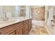Bathroom featuring double sinks with wood cabinets, a tub with a tiled surround, and neutral decor at 11630 Flynn Ct, Winter Garden, FL 34787
