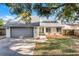 Charming one-story home with a gray roof, a gray garage door, and mature trees at 1220 Rolling Ln, Casselberry, FL 32707