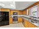 Kitchen featuring stainless steel appliances, wooden cabinetry, granite counters, and a double-basin sink at 1220 Rolling Ln, Casselberry, FL 32707