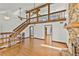 Open living room with hardwood flooring, exposed wood beams, a stone fireplace, and a staircase at 1220 Rolling Ln, Casselberry, FL 32707