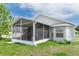 View of the screened-in patio with gray siding and a grassy yard at 13624 Springtide Ct, Orlando, FL 32826