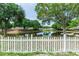 Tranquil backyard pond view framed by a classic white picket fence and lush green trees at 13624 Springtide Ct, Orlando, FL 32826